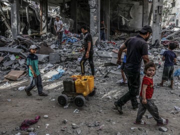 Refugiados palestinos caminan entre los escombros en Rafah