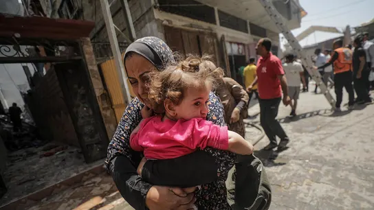 Una mujer palestina que sostiene a un niño en brazos huye del lugar tras un ataque aéreo israelí en el campo de refugiados de Al Nuseirat, en el centro de la Franja de Gaza. Una mujer palestina que sostiene a un niño en brazos huye del lugar tras un ataque aéreo israelí en el campo de refugiados de Al Nuseirat, en el centro de la Franja de Gaza.