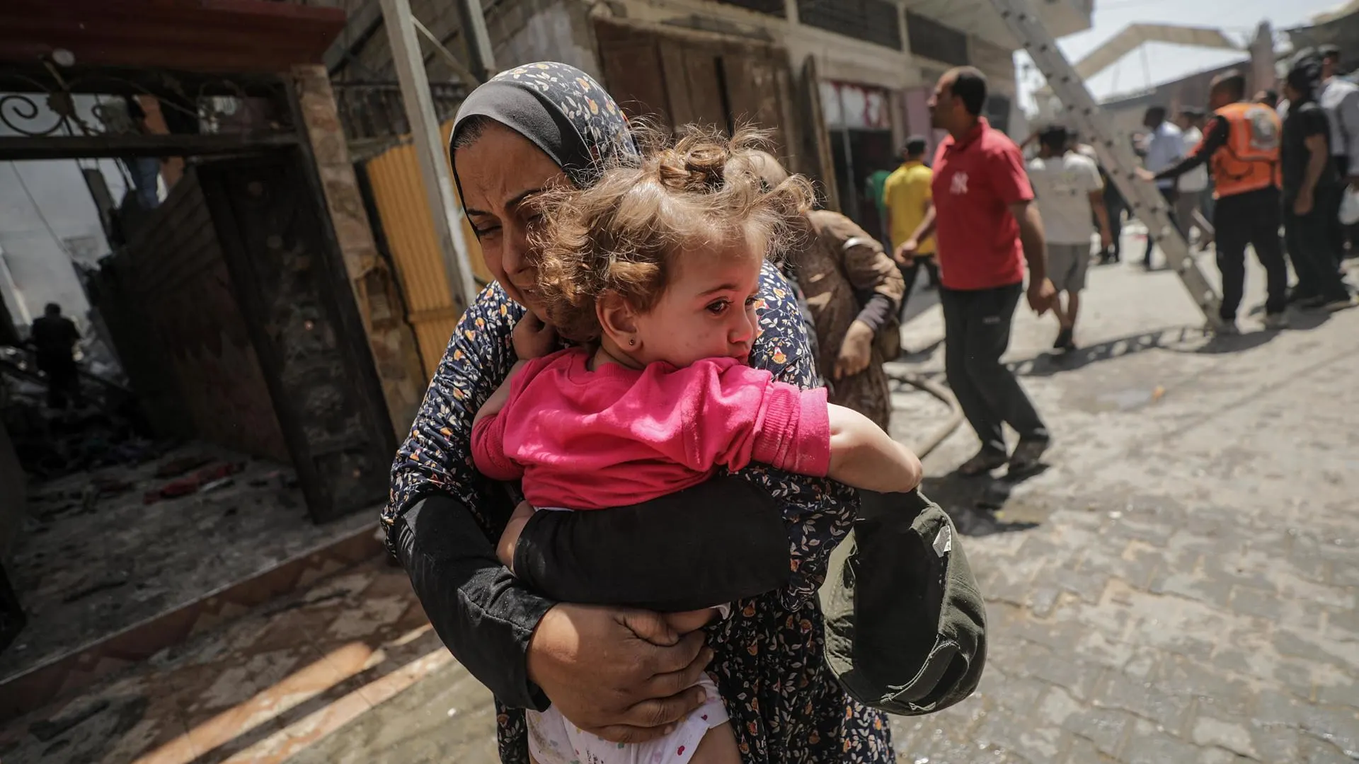 Una mujer palestina que sostiene a un niño en brazos huye del lugar tras un ataque aéreo israelí en el campo de refugiados de Al Nuseirat, en el centro de la Franja de Gaza.