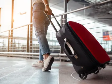 Chica con una maleta roja en el aeropuerto Chica con una maleta roja en el aeropuerto