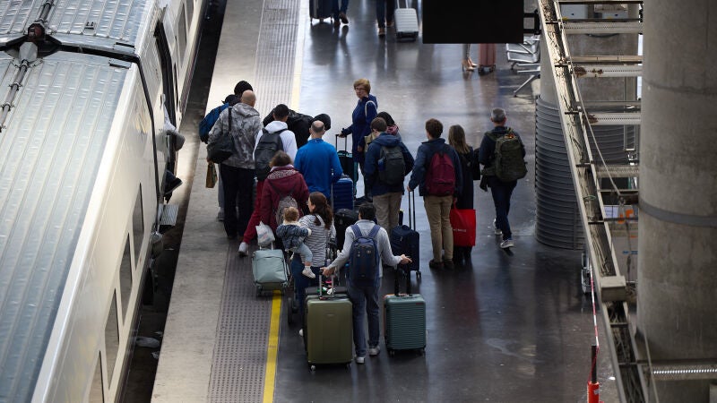 Varias personas esperan a un tren en un andén con motivo de la segunda fase de la operación Salida por Semana Santa en la Estación de Atocha, a 27 de marzo de 2024, en Madrid (España). 