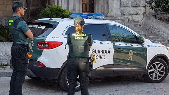 Dos agentes de la Guardia Civil junto a un coche oficial Dos agentes de la Guardia Civil junto a un coche oficial