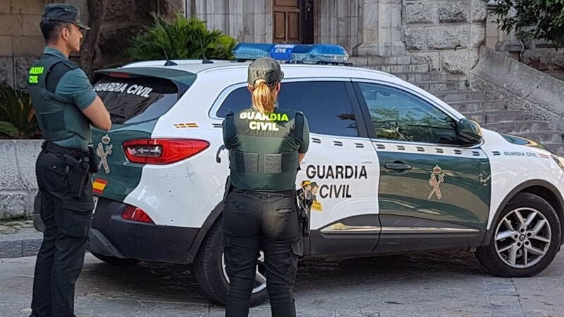 Dos agentes de la Guardia Civil junto a un coche oficial