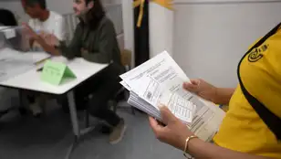Una trabajadora de correos porta los votos por correo para entregarlos al presidente de mesa a primera hora en el Institut Escola Projecte de Barcelona.