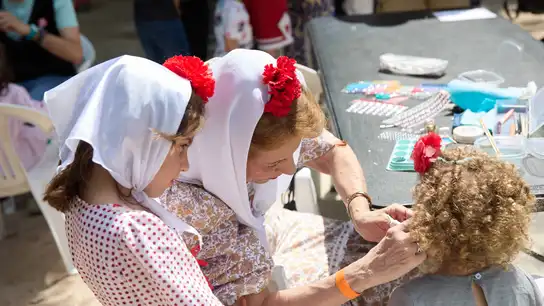 Una chulapa con su pañuelo y su clavel colocando claveles a dos pequeñas chulapas por San Isidro Una chulapa con su pañuelo y su clavel colocando claveles a dos pequeñas chulapas por San Isidro