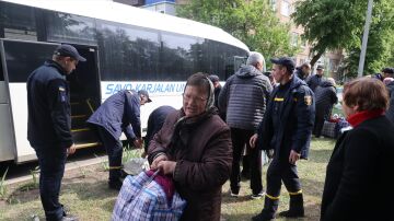 Una anciana lleva una bolsa junto a un autobús para evacuar personas desde la región de Járkov.