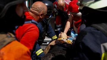 Trabajadores de emergencia llevan a una persona herida a una ambulancia en el lugar de una estructura turística alcanzada por un misil ruso, en medio del ataque de Rusia a Ucrania, en Járkiv, el 19 de mayo de 2024. 