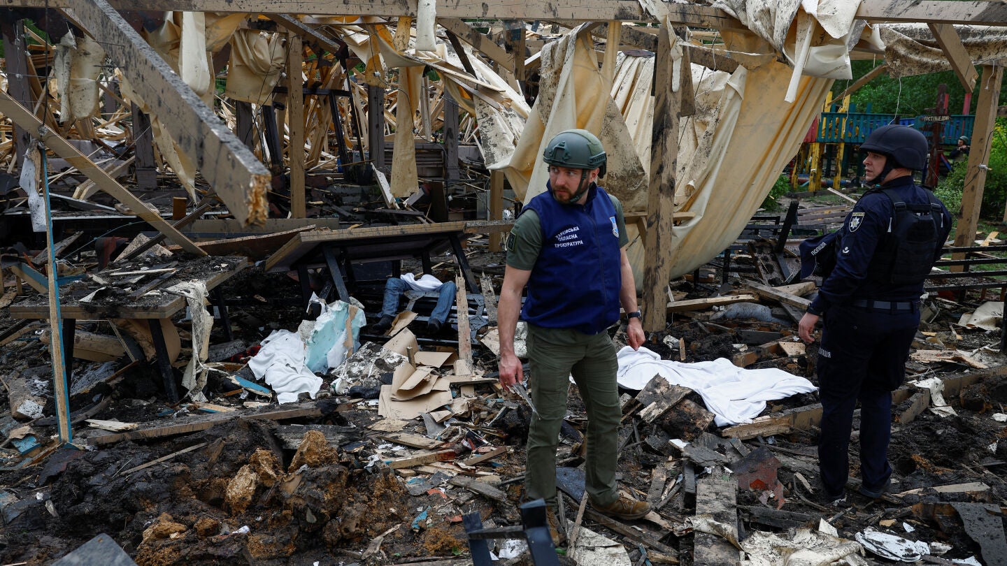Un fiscal de crímenes de guerra y un oficial de policía se encuentran junto a los cuerpos de las personas muertas por un ataque con misiles rusos contra un complejo turístico en Kharkiv, en medio del ataque de Rusia contra Ucrania el 19 de mayo de 2024. 