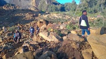 Algunas personas recogen sus enseres de entre las rocas que han sepultado su aldea en Papúa New Guinea.