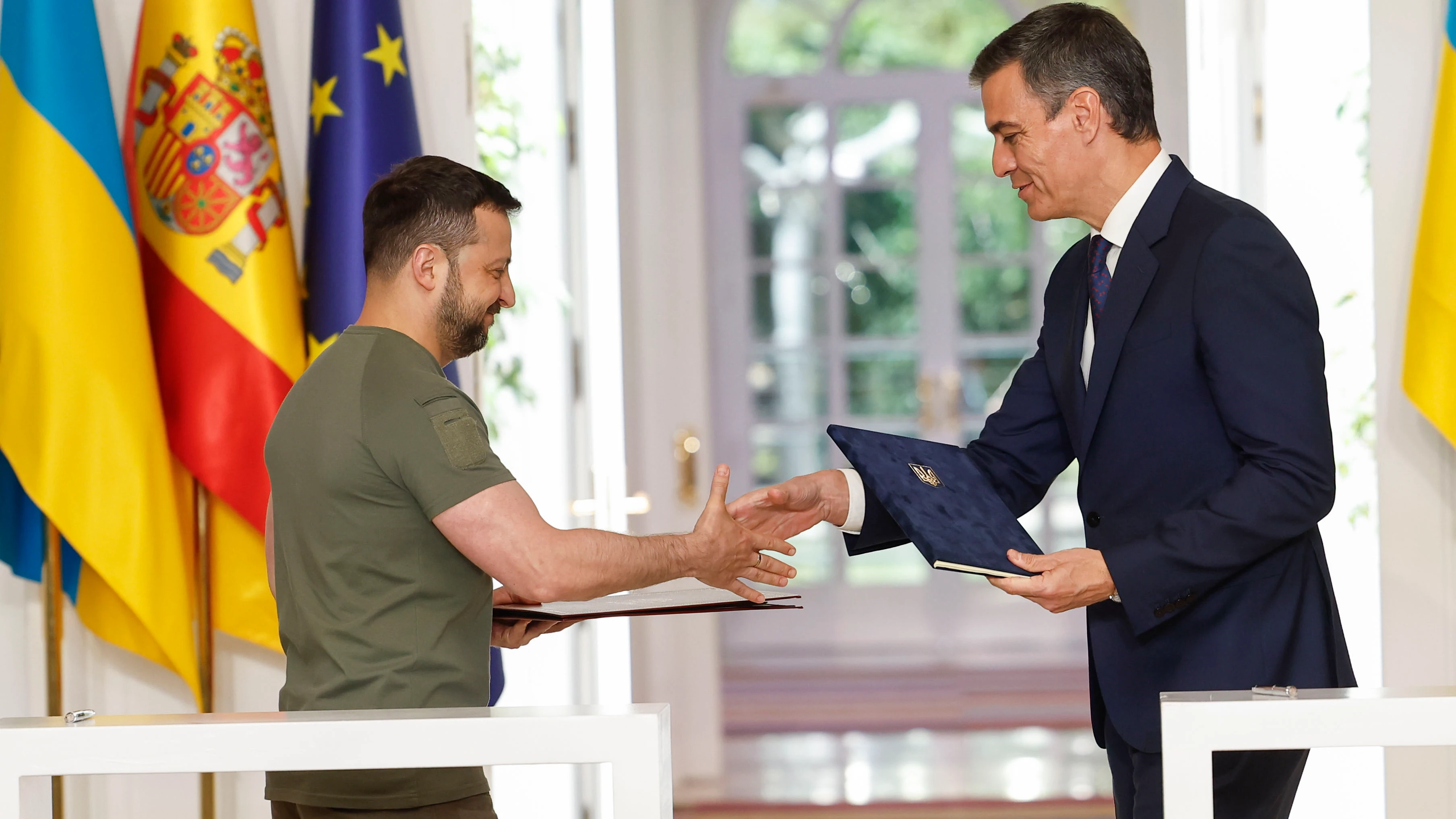 El presidente del gobierno español, Pedro Sánchez (d), y el presidente de Ucrania, Volodímir Zelenski​, estrechan sus manos después de firmar el "Acuerdo de Cooperación en materia de Seguridad entre España y Ucrania" este lunes en el palacio de La Moncloa en Madrid.