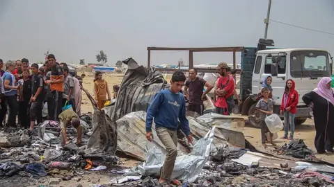 Palestinos entre los restos de un incendio provocado por un bombardeo israelí contra un campamento de desplazados en Rafah Palestinos entre los restos de un incendio provocado por un bombardeo israelí contra un campamento de desplazados en Rafah