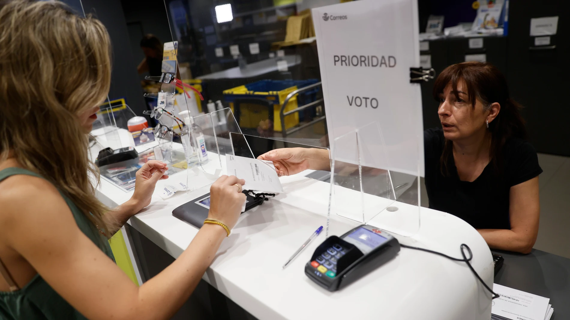 Imagen de archivo de una mujer entregando la documentación para ejercer el voto por correo en una oficina de Madrid. 