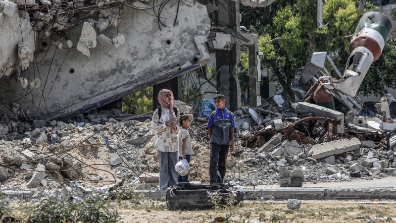 Niños palestinos ante edificios destruidos por ataques israelíes en el centro de Gaza