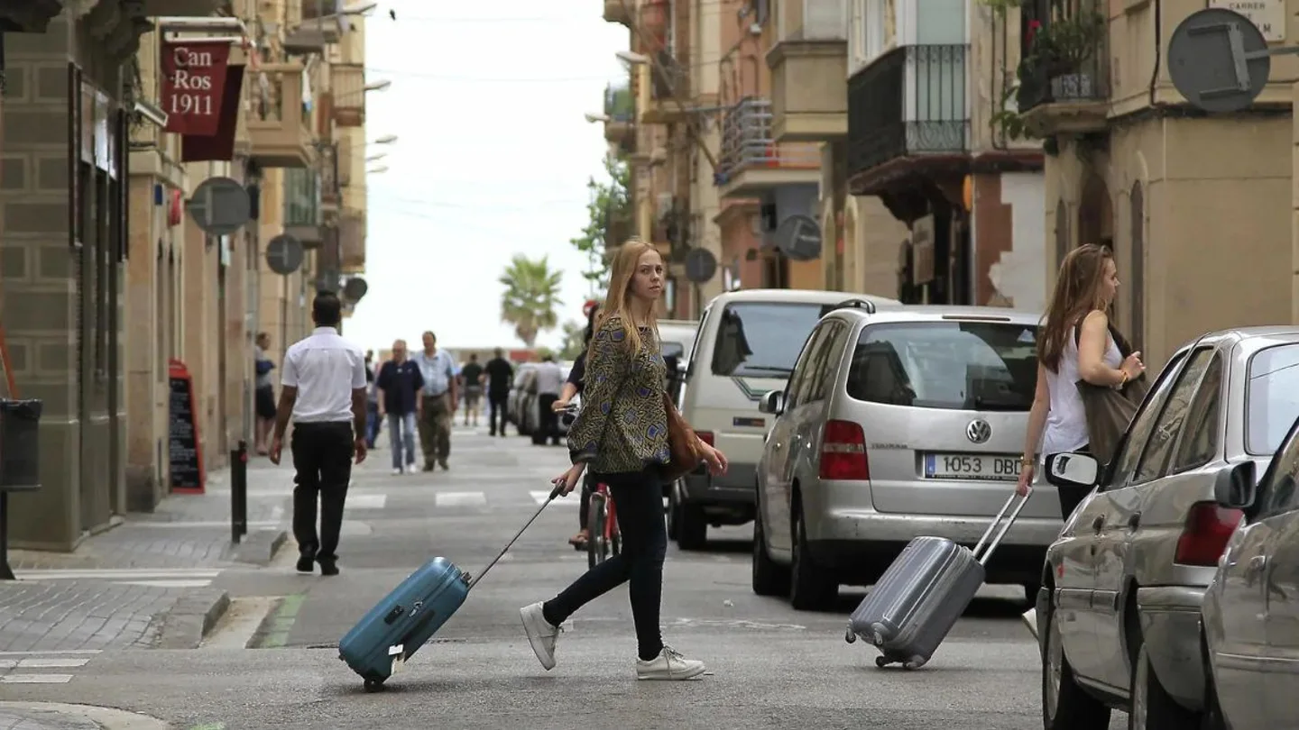 Unas turistas buscan su hospedaje en una zona de apartamentos turísticos Unas turistas buscan su hospedaje en una zona de apartamentos turísticos