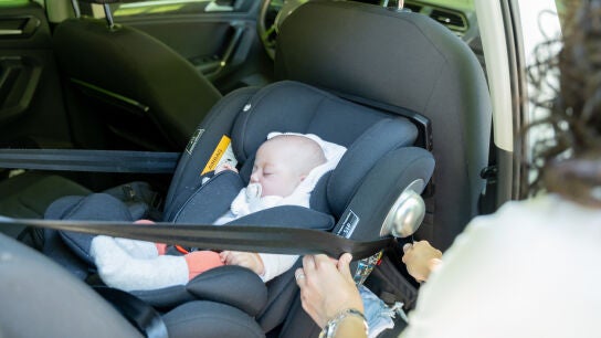 Una mujer ajusta una sillita infantil en el coche.