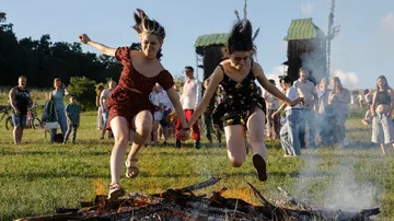 Jóvenes ucranianas saltan sobre una hoguera durante las celebraciones de la tradicional festividad pagana de Ivana Kupala, en Kyiv, Ucrania, el 23 de junio de 2024. 