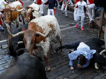 Un mozo y un toro caen durante el segundo encierro de los Sanfermines protagonizados por la ganadería de los Herederos de D. José Cebada Gago, de Medina Sidonia (Cádiz), este lunes en Pamplona.