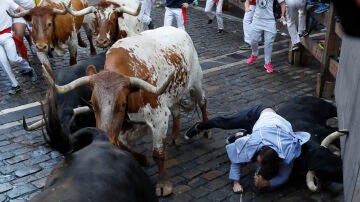 Un mozo y un toro caen durante el segundo encierro de los Sanfermines protagonizados por la ganadería de los Herederos de D. José Cebada Gago, de Medina Sidonia (Cádiz), este lunes en Pamplona.