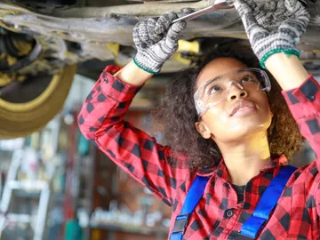 Mujer trabajando en un taller mecánico de coches. Mujer trabajando en un taller mecánico de coches.