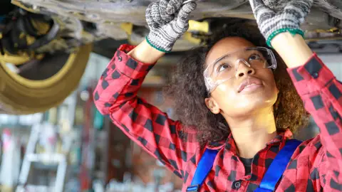 Mujer trabajando en un taller mecánico de coches. Mujer trabajando en un taller mecánico de coches.