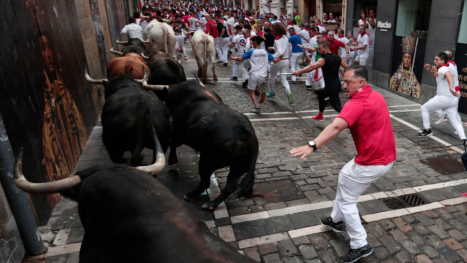 Los toros de la ganadería de Fuente Ymbro pasan por la curva de Mercaderes y enfilan la calle de la Estafeta en el cuarto encierro de los Sanfermines este miércoles, en Pamplona.