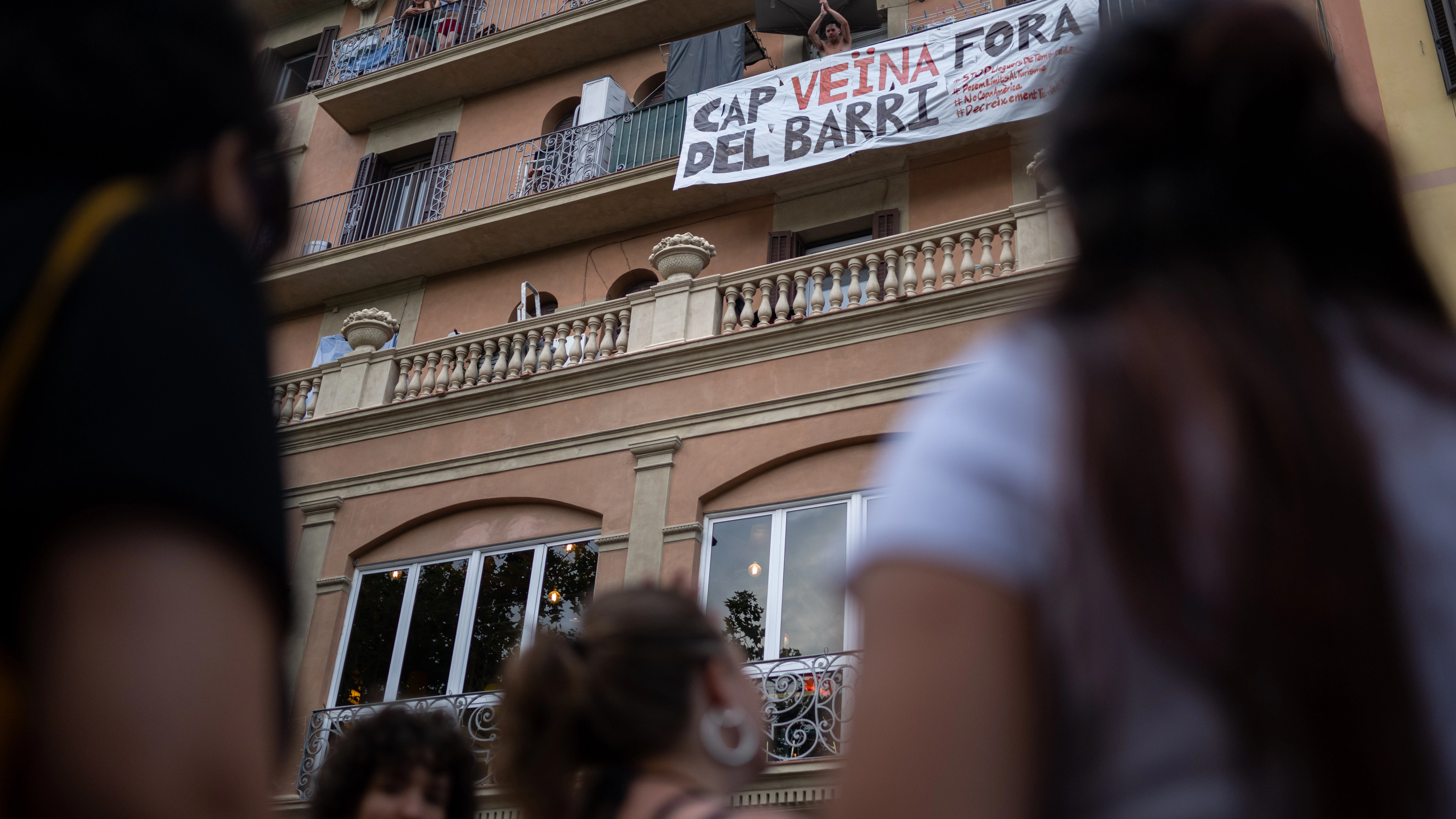 Un hombre con una pancarta en su balcón durante una manifestación contra el turismo masificado