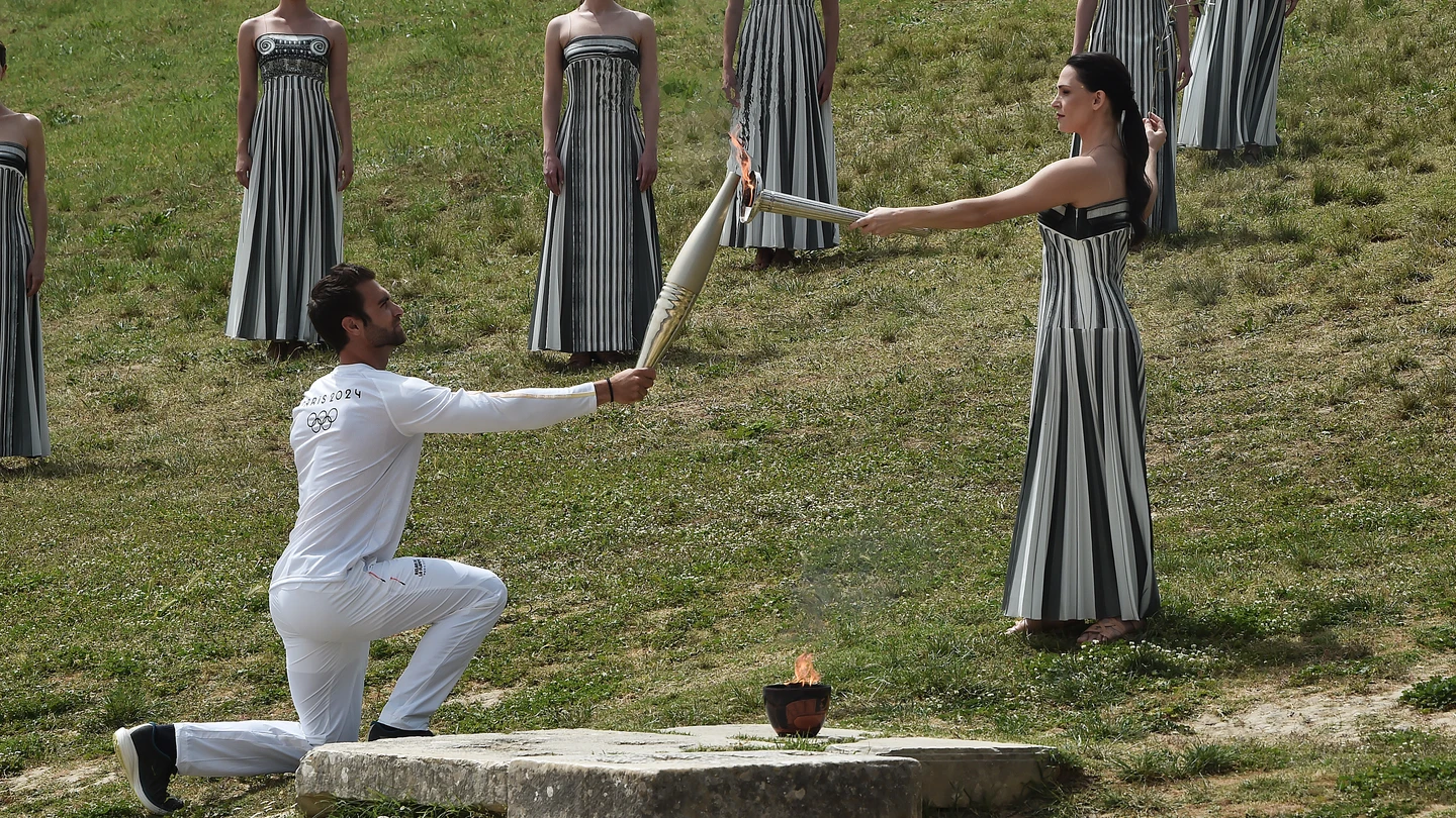 Stephanos Ntouskos, primer portador griego de la antorcha, recibe la llama de manos de la actriz griega Mary Mina, que interpreta el papel de la Gran Sacerdotisa, durante la ceremonia de encendido de la llama de los Juegos Olímpicos de Verano de París 2024. Stephanos Ntouskos, primer portador griego de la antorcha, recibe la llama de manos de la actriz griega Mary Mina, que interpreta el papel de la Gran Sacerdotisa, durante la ceremonia de encendido de la llama de los Juegos Olímpicos de Verano de París 2024.