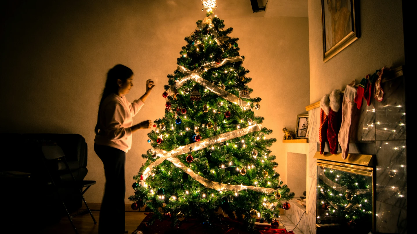 Una niña decora un árbol de Navidad. Una niña decora un árbol de Navidad.