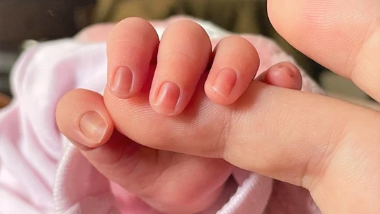 Un bebé de pocos días de edad coge el dedo de su madre. Un bebé de pocos días de edad coge el dedo de su madre.