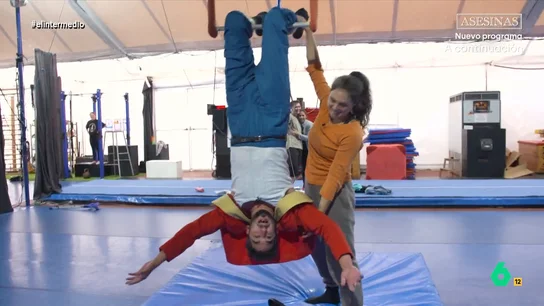 La 'propuesta' de Zenaida, profesora de trapecio, a Isma Juárez: "¿Quieres conocer el dolor?" El reportero se atreve a probar el trapecio, un elemento clásico del circo. A pesar de sus miedos, el reportero consigue colgarse del trapecio e, incluso, suelta las manos.