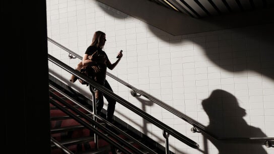 Una mujer bajando unas escaleras mientras mira el m&oacute;vil. 