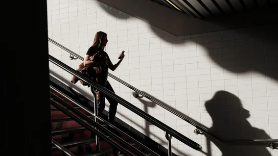 Una mujer bajando unas escaleras mientras mira el móvil. Una mujer bajando unas escaleras mientras mira el móvil.