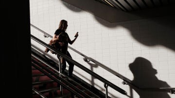 Una mujer bajando unas escaleras mientras mira el m&oacute;vil. 