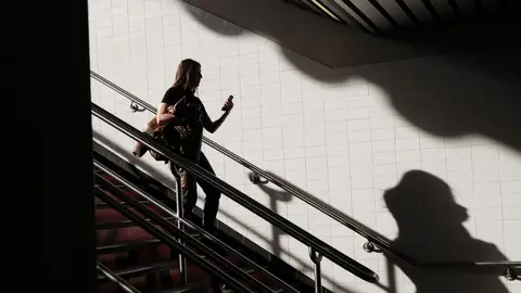 Una mujer bajando unas escaleras mientras mira el móvil. Una mujer bajando unas escaleras mientras mira el móvil.