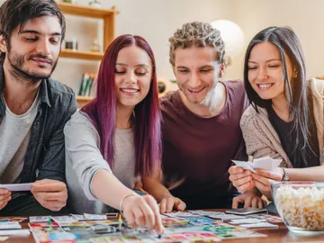 Un grupo de amigos se divierte con un juego de mesa Un grupo de amigos se divierte con un juego de mesa