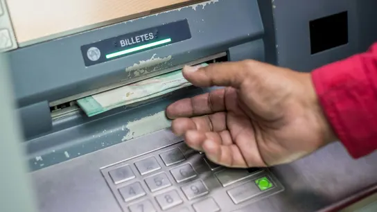 Una persona retira dinero del cajero automático de un banco Una persona retira dinero del cajero automático de un banco