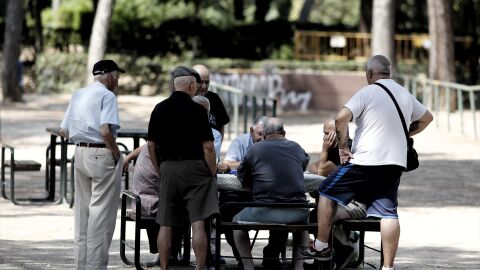 Varios pensionistas juegan al domin&oacute; en un parque de Madrid.