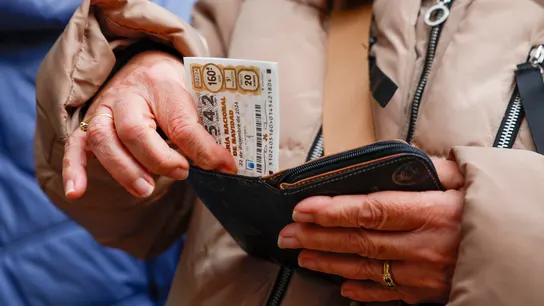 Una persona guarda un billere de lotería de Navidad en su cartera. Una persona guarda un billere de lotería de Navidad en su cartera.