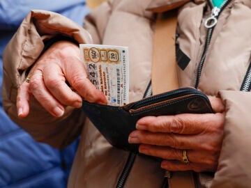 Una persona guarda un billere de lotería de Navidad en su cartera.