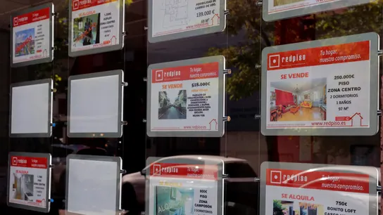 Imagen de archivo de anuncios de pisos y casas en venta y alquiler en el escaparate de una inmobiliaria.  Imagen de archivo de anuncios de pisos y casas en venta y alquiler en el escaparate de una inmobiliaria.