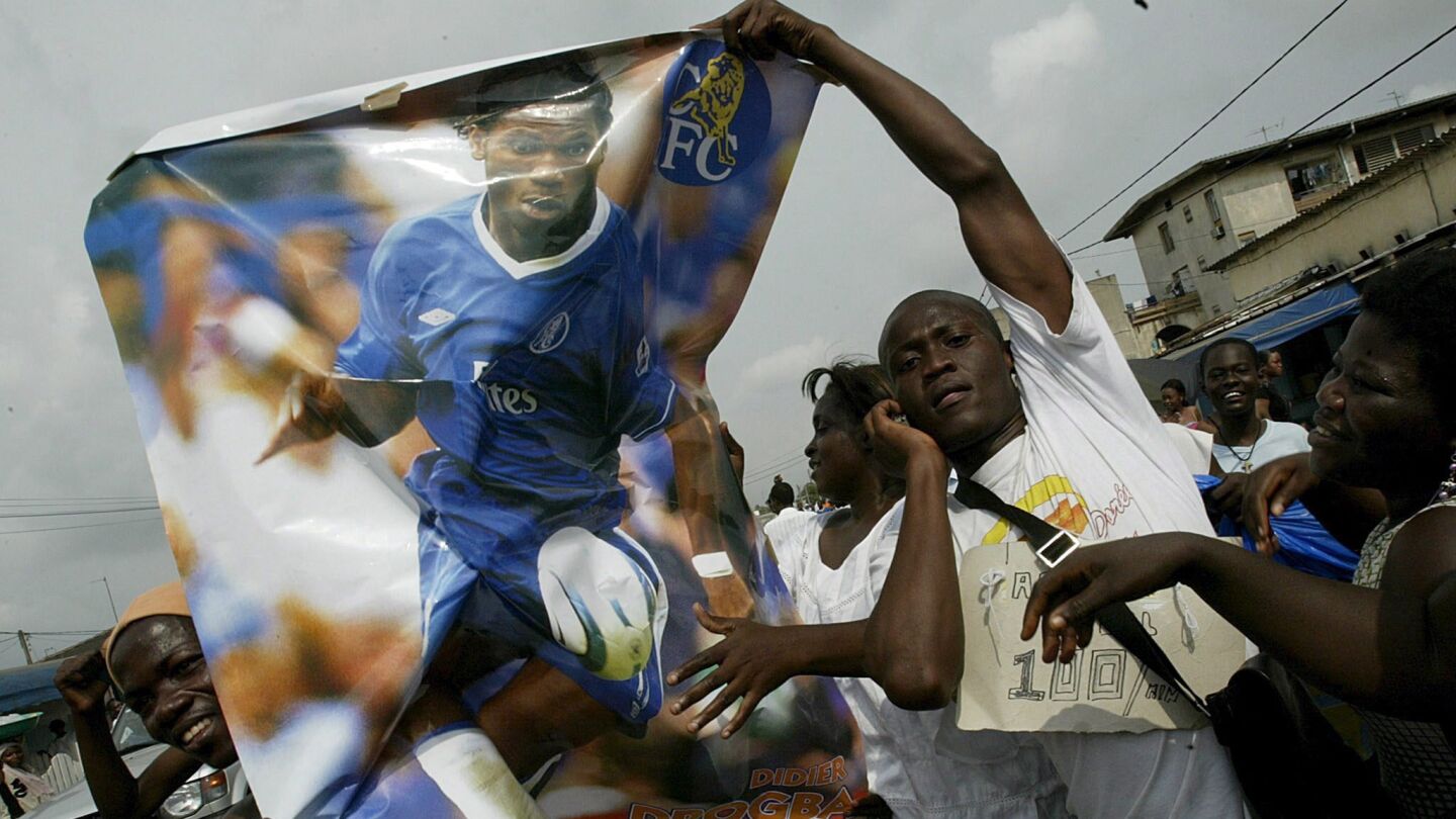 Un grupo de aficionados marfile&ntilde;os sostienen un poster del goleador Didier Drogba, en 2006
