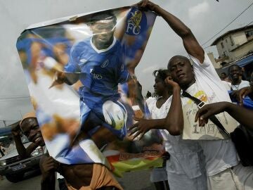 Un grupo de aficionados marfileños sostienen un poster del goleador Didier Drogba, en 2006