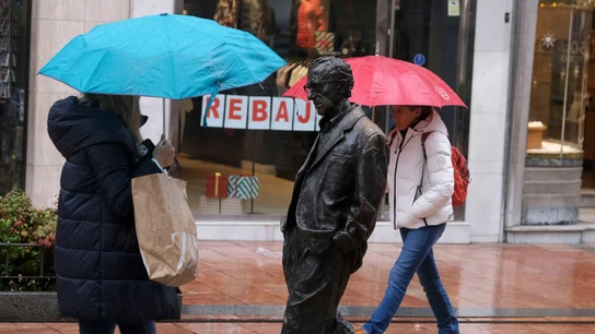 Paseantes se protegen de la intensa lluvia junto a la estatua de Woody Allen en el centro de Oviedo este jueves. Paseantes se protegen de la intensa lluvia junto a la estatua de Woody Allen en el centro de Oviedo este jueves.