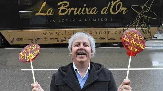 Xavier Gabriel, fundador de la administración La Bruixa d'Or en Sort (Lleida), frente a la fachada de su negocio. Xavier Gabriel, fundador de la administración La Bruixa d'Or en Sort (Lleida), sostiene dos piruletas con sus números de lotería.