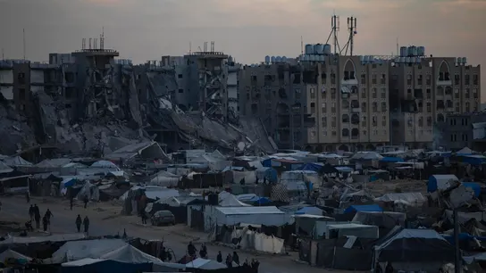 Palestinos desplazados caminan entre tiendas de campaña en un campamento improvisado en Jan Yunis Palestinos desplazados caminan entre tiendas de campaña en un campamento improvisado en Jan Yunis