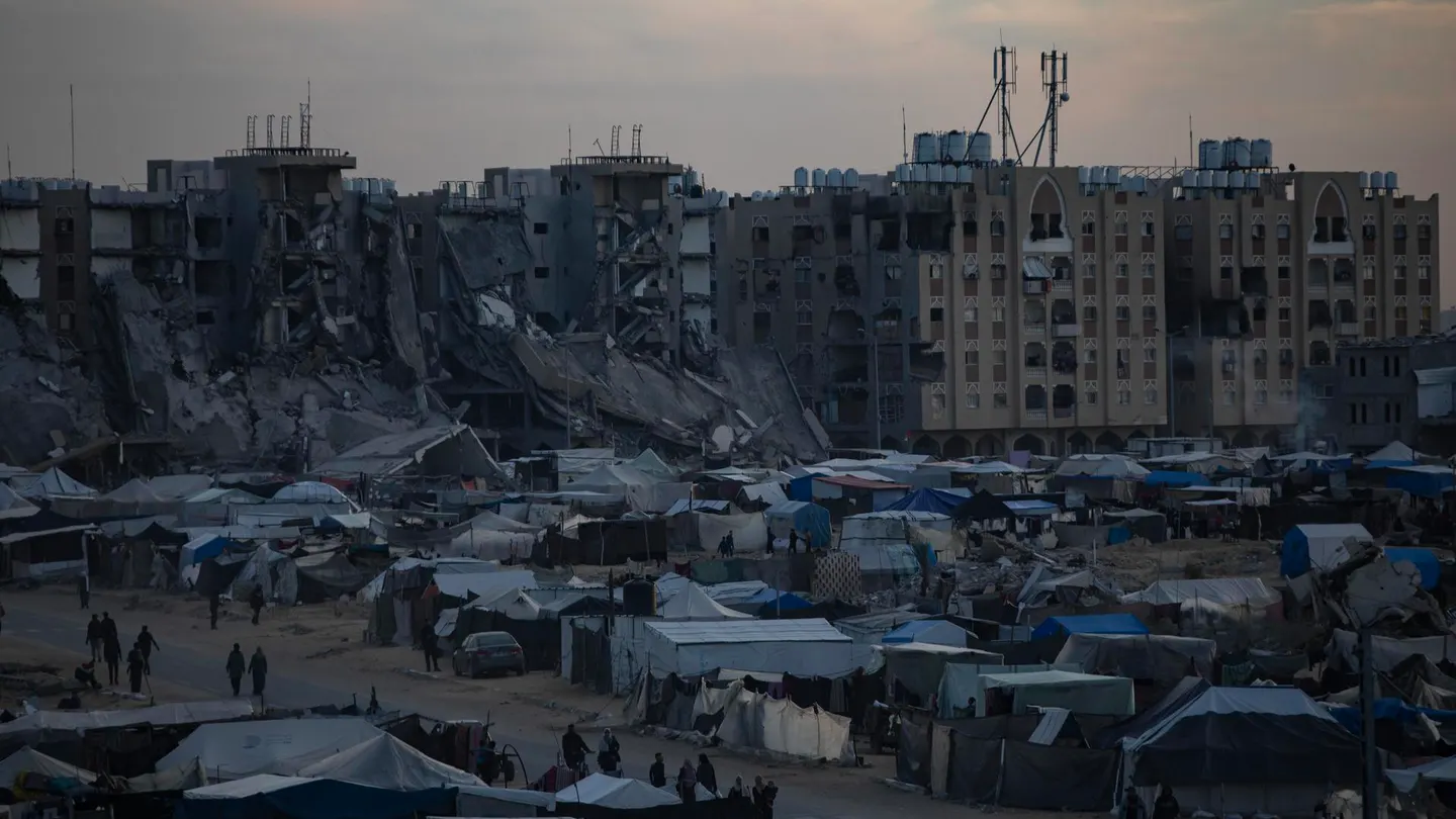 Palestinos desplazados caminan entre tiendas de campaña en un campamento improvisado en Jan Yunis Palestinos desplazados caminan entre tiendas de campaña en un campamento improvisado en Jan Yunis