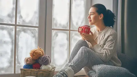 Mujer mirando por la ventana en invierno Mujer mirando por la ventana en invierno