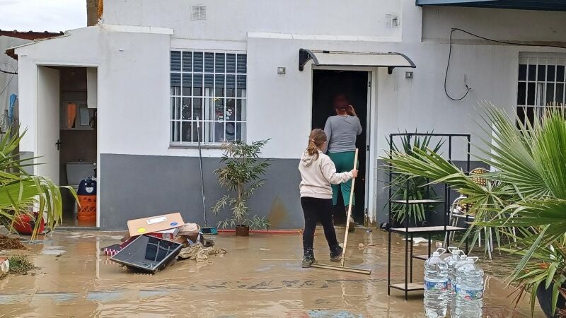 Unas personas limpian su casa tras las lluvias caídas en Huelva