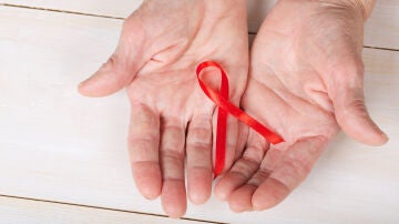 Manos de persona mayor y el lazo contra el VIH