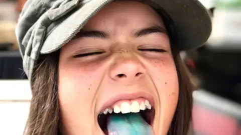 NIña con la lengua pintada de azul  NIña con la lengua pintada de azul